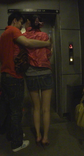 街拍牛仔短裙裸腿高跟美眉与男友在电梯前的暧昧