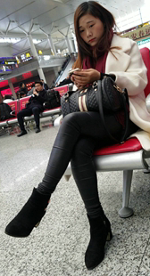 高铁站候车的黑色紧身皮裤长发少妇