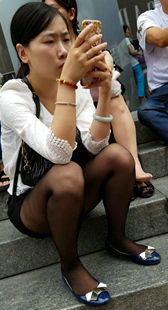 坐在地上玩手机的黑丝短裤MM